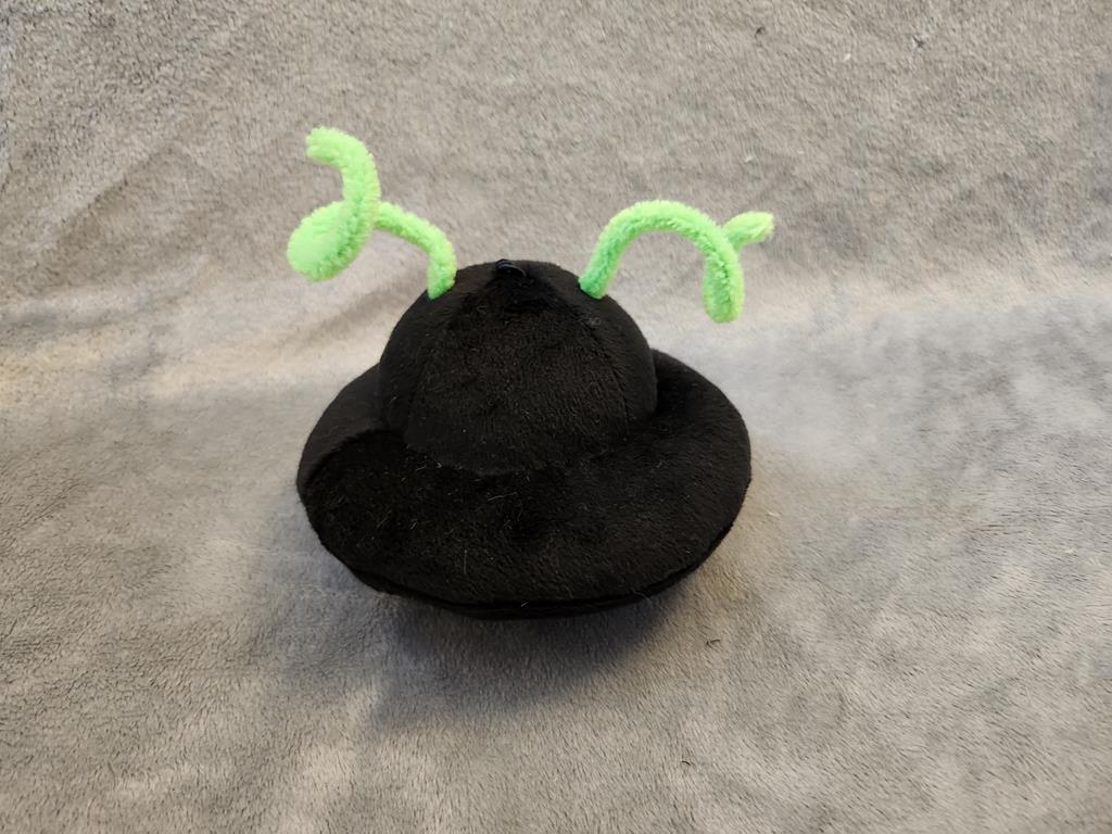 A black flying saucer with green antennae